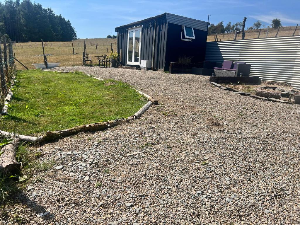 a tiny house on a gravel road next to a building at Cabin on the Moors in Llansannan