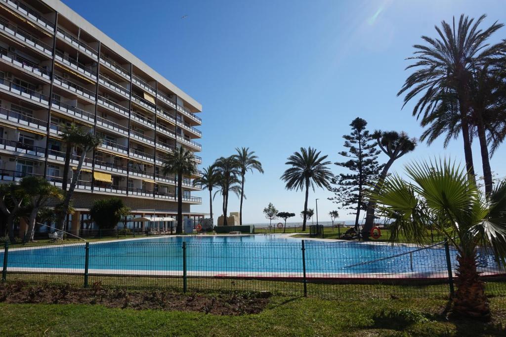 einem Pool mit Palmen vor einem Gebäude in der Unterkunft Castillo de Santa Clara in Torremolinos