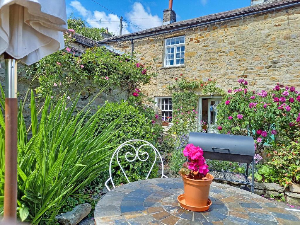 a table with a chair and flowers in front of a building at Lock Heather Cottage in Reeth