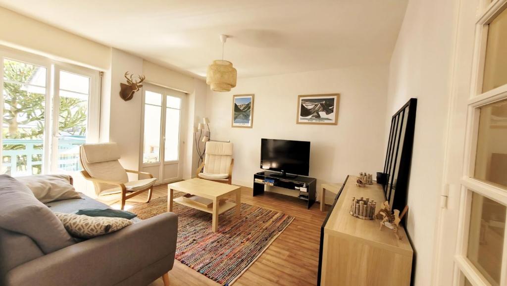 a living room with a couch and a tv at Appartement plein Centre Cauterets, Vacances et Cures in Cauterets