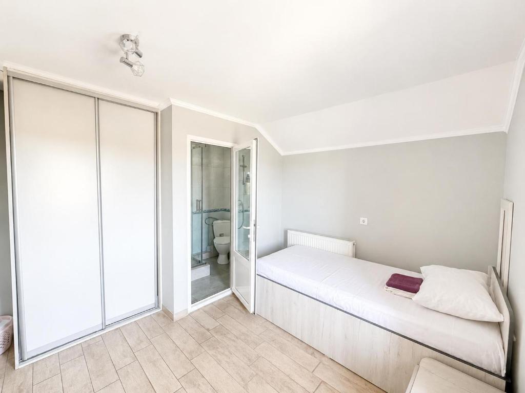 a white bedroom with a bed and a bathroom at Hotel Dulgher in Giurgiuleşti