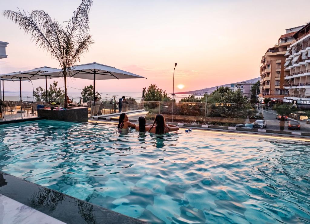 two women laying in a swimming pool on a building at Hotel Oasis in Sarandë