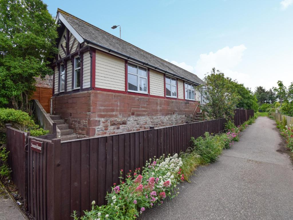 a brick house with a fence and flowers at Station House in St Bees