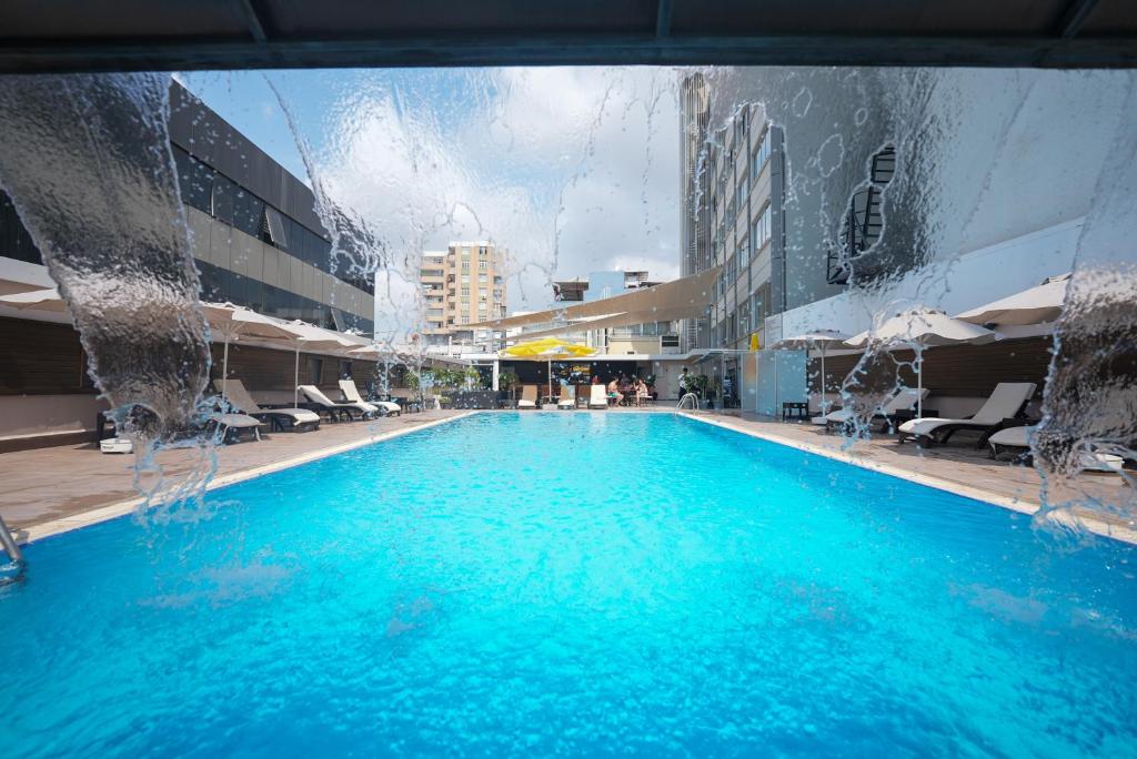 a large swimming pool with blue water in a building at Surmeli Adana Hotel in Adana