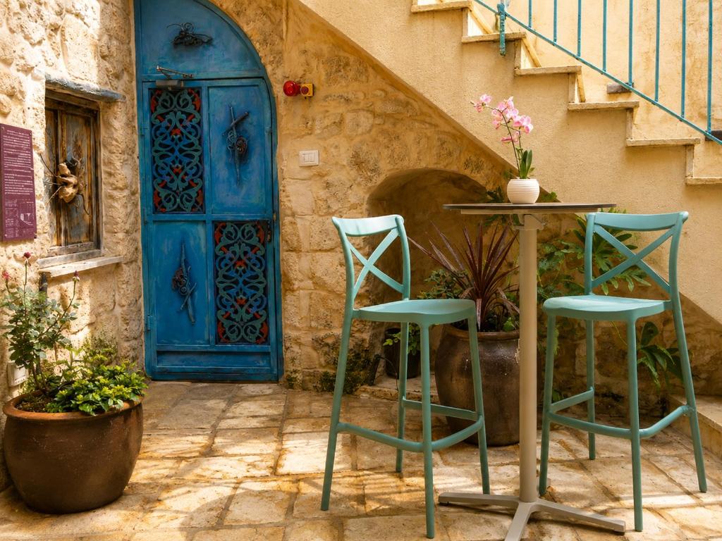 a table and two chairs in front of a blue door at El Khan Guesthouse & Art - A Complex of 4 Middle Eastern-Style Suites in Nazareth