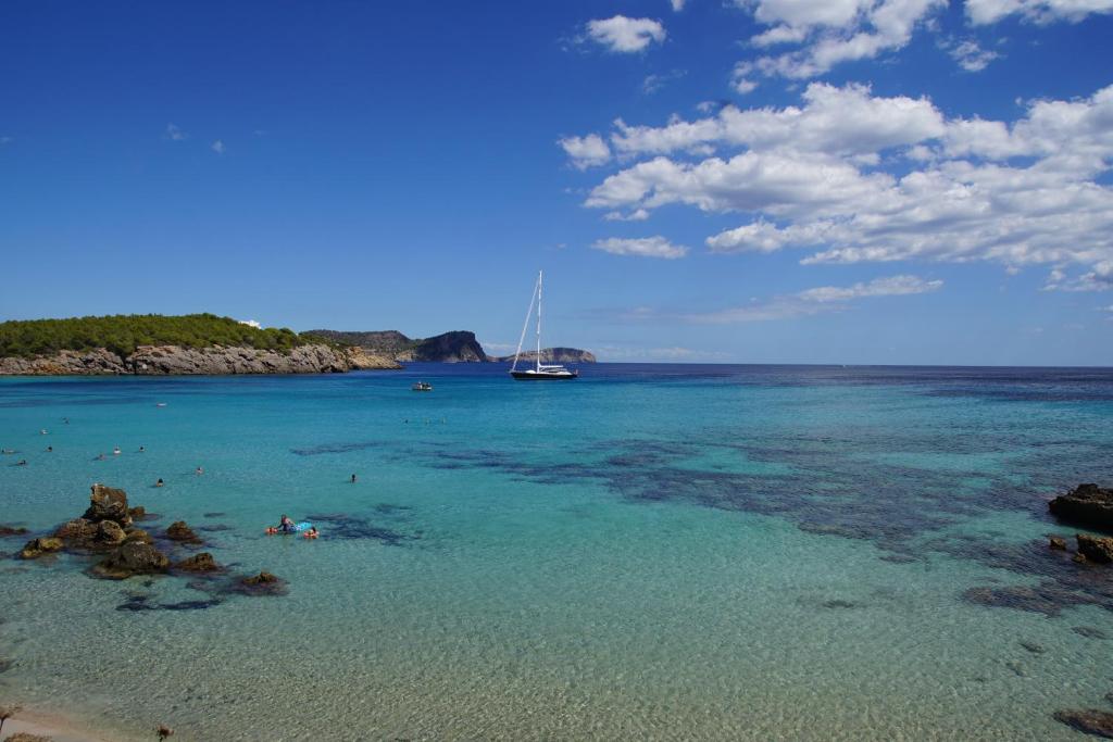 vistas a una playa con un barco en el agua en Camping Cala Nova, en Es Canar