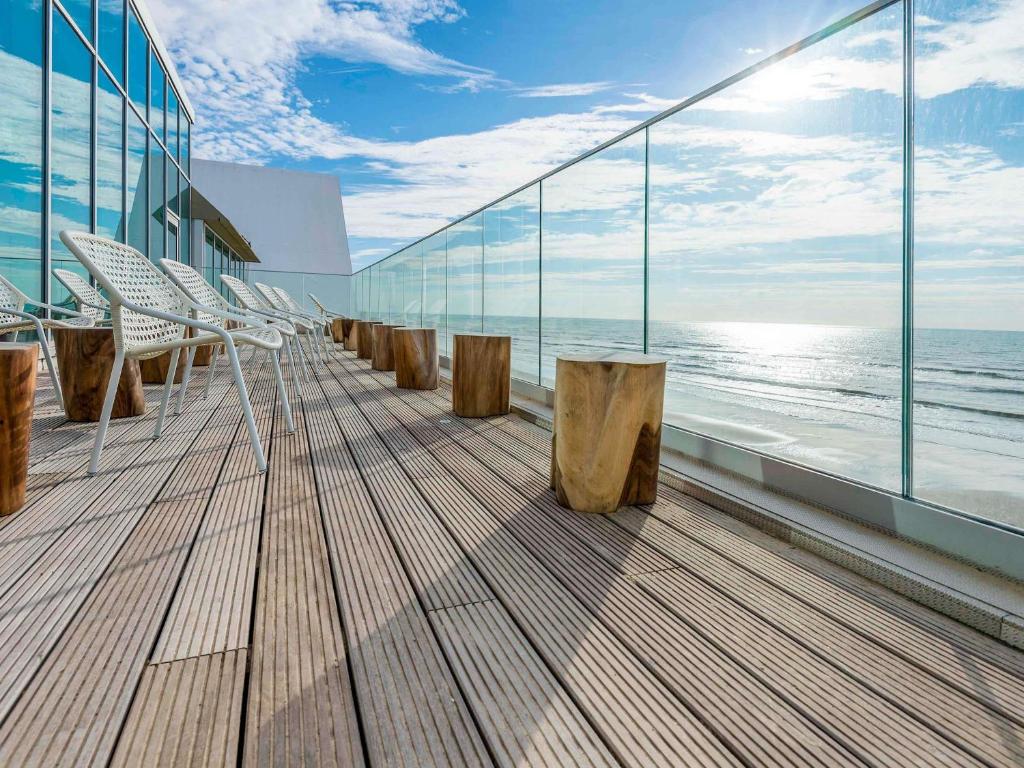 a deck on a cruise ship with chairs and the ocean at Novotel Thalassa Le Touquet in Le Touquet-Paris-Plage