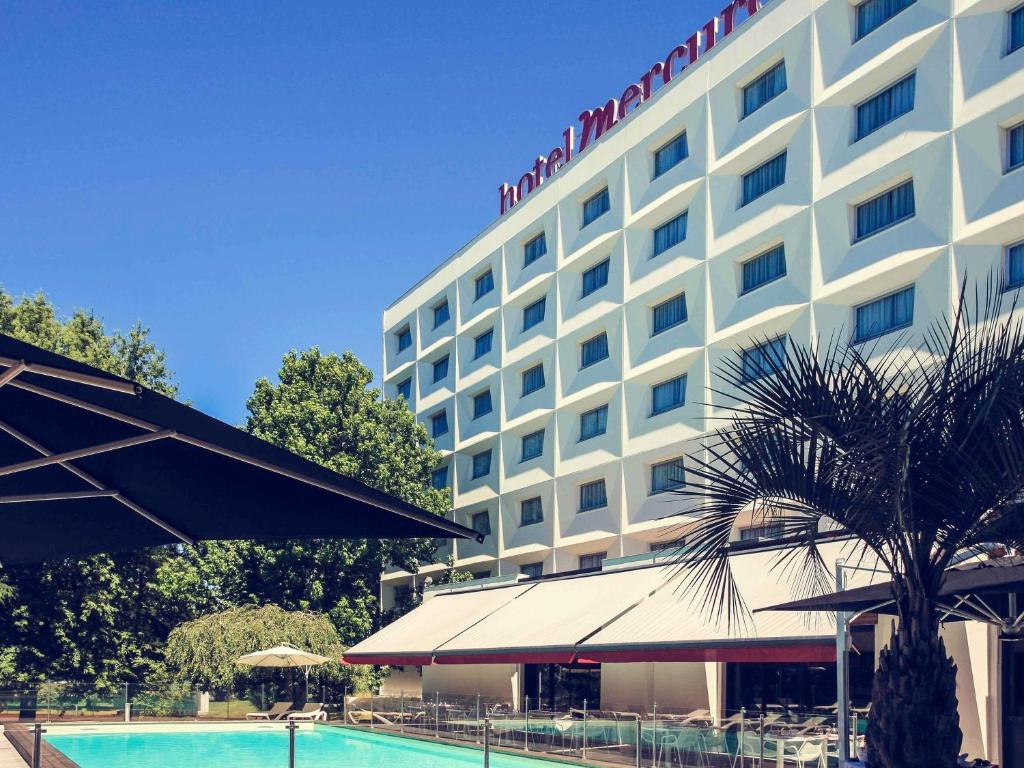 a hotel with a swimming pool in front of it at Mercure Bordeaux Lac in Bordeaux