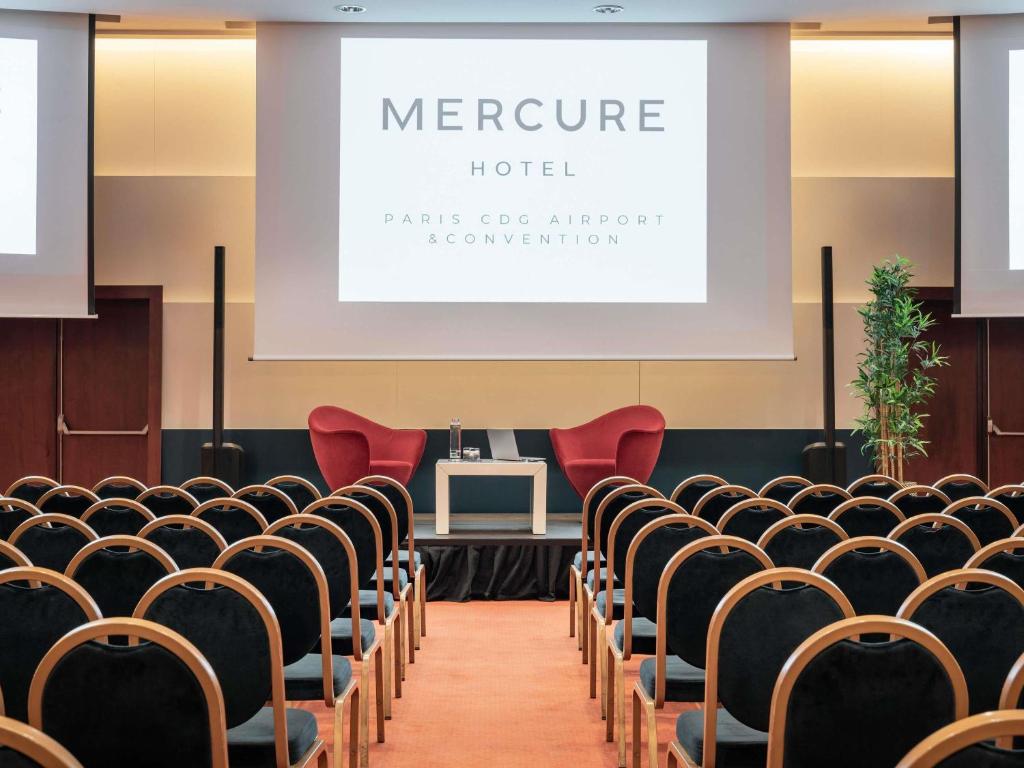 a lecture hall with chairs and a screen at Mercure Paris CDG Airport & Convention in Roissy-en-France