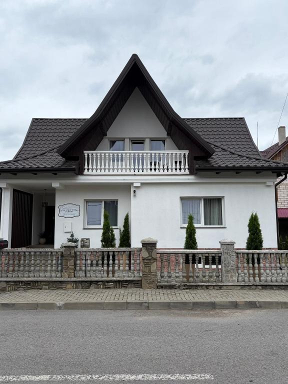 a white house with a black roof and a fence at Vacation with Purpose in Gura Humorului