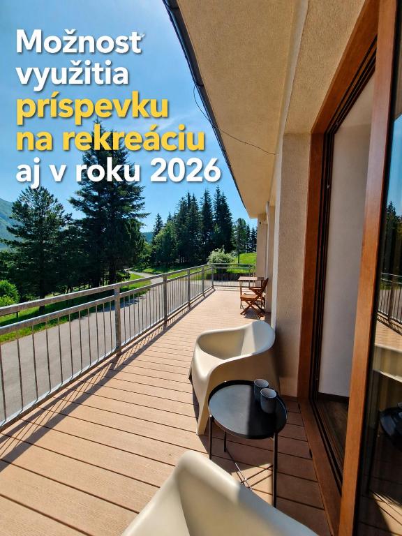a balcony with two chairs and a view of the water at Apartmán Kľak in Fačkov