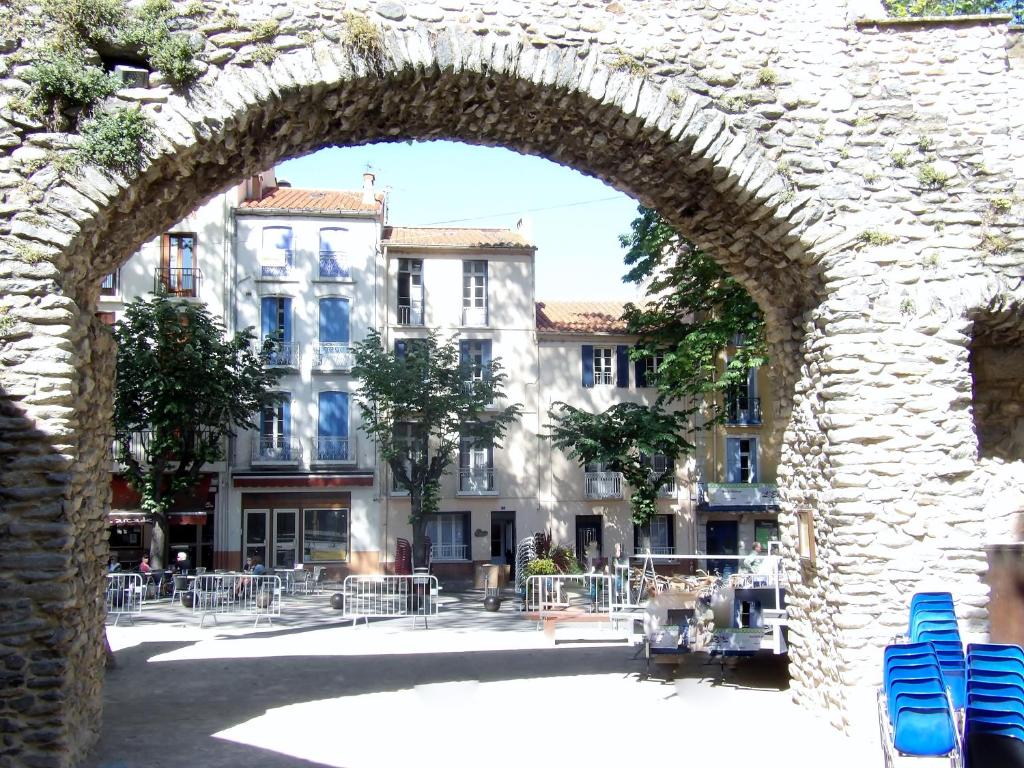 uma arcada num edifício com cadeiras num pátio em Poppys Chambres d'Hotes em Céret