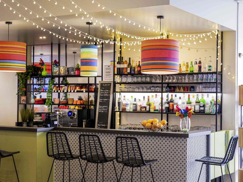 a bar with a counter with chairs and lights at ibis Styles Perpignan Centre Gare in Perpignan