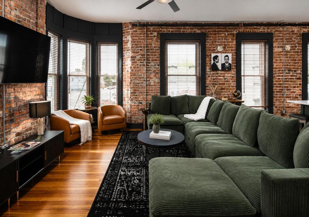 a living room with a green couch and a brick wall at Best Intentions in Port Clinton