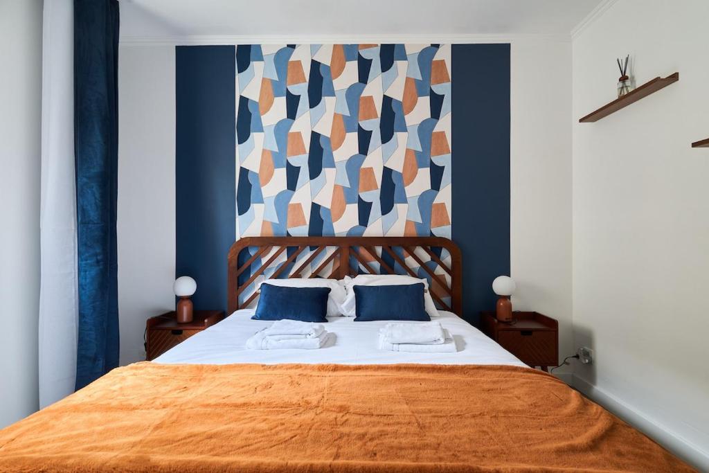 a bedroom with a bed with blue and orange sheets at MM Suites Town House Terrasse in Reims
