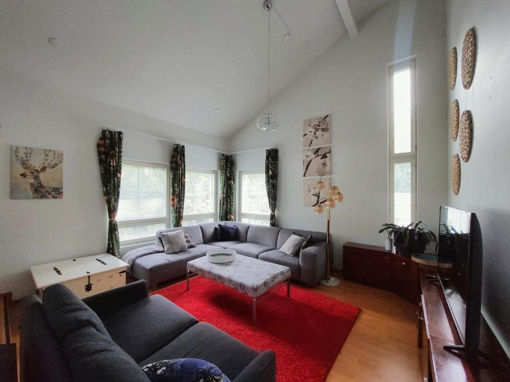 a living room with a couch and a red rug at Semi-detached house with sauna & yard near city center in Hyvinkää