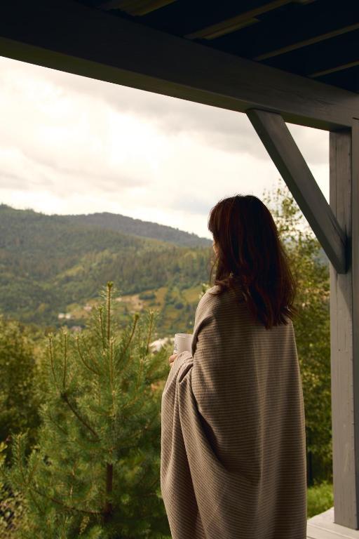 a woman standing on a porch looking out at the mountains at Лісогори in Slavske