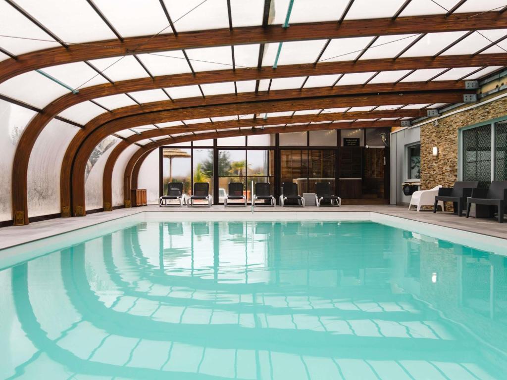 a large swimming pool with a retractable ceiling at Mercure Cabourg Hôtel & Spa in Cabourg