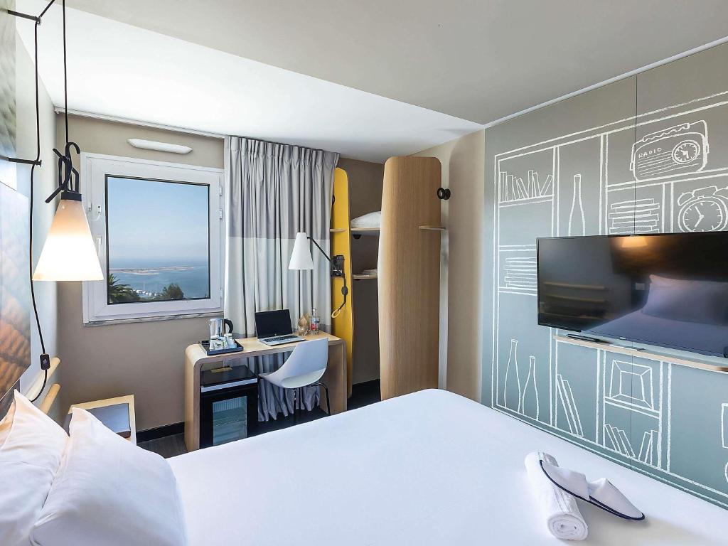 a hotel room with a bed and a desk with a television at Hotel ibis Porto Gaia in Vila Nova de Gaia