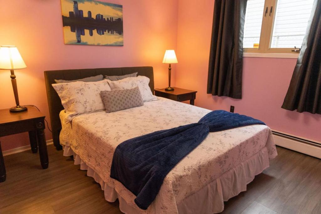 a bedroom with a bed with two lamps and two windows at Tranquil Retreats on Robinson in Moncton