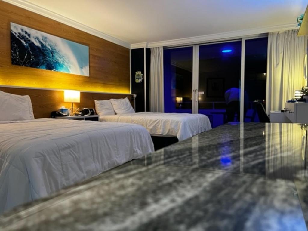 a hotel room with two beds and a window at Ocean Manor Tiki Sunset Retreat in Fort Lauderdale