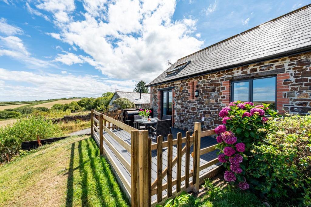 a brick house with a wooden fence and flowers at Trespaddick, coastal views Treworgie Barton in Bude