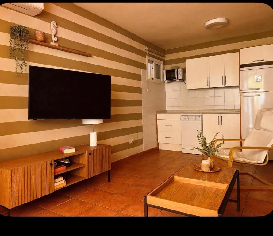 a living room with a flat screen tv on a striped wall at Gladiolos San Agustin Beach in San Agustin