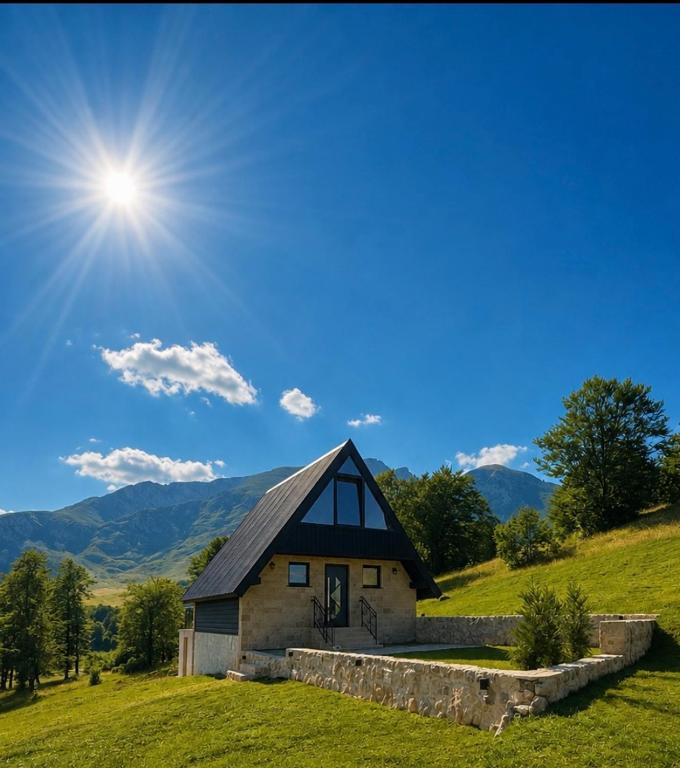 a house on a hill with the sun in the sky at Monte Casa Žabljak in Žabljak