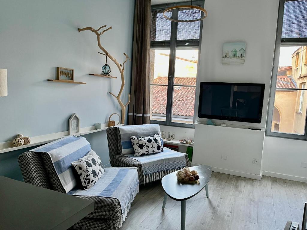 a living room with two chairs and a tv at La loge des Salinières in Bordeaux