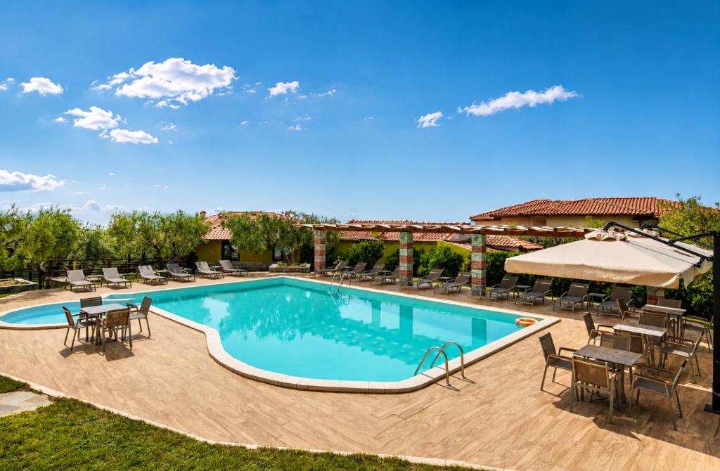 a swimming pool with tables and chairs and a patio at Sunday Resort in Gerakini