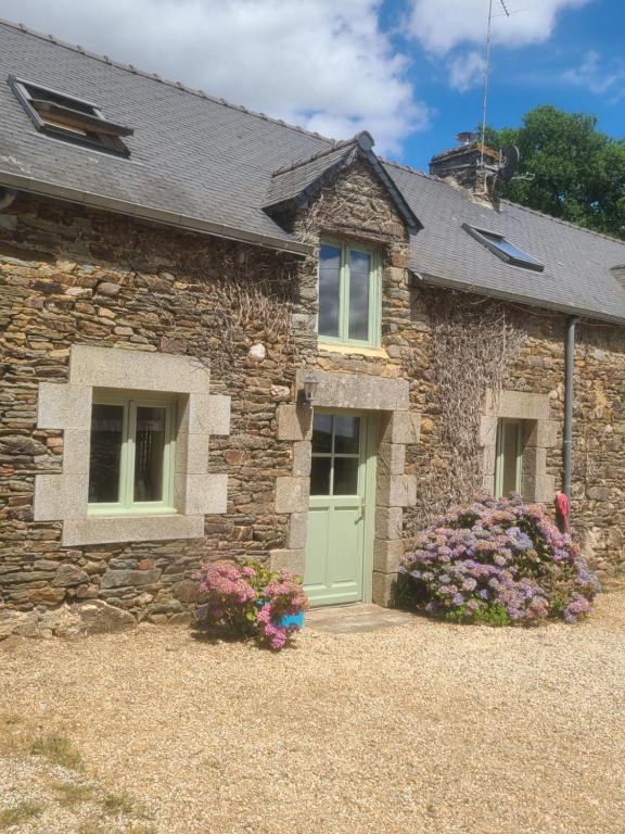 a stone house with a green door and flowers at Clipgites in Pleugriffet