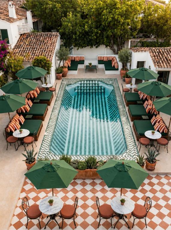 an overhead view of a swimming pool with tables and green umbrellas at BV House - Membersclub - Adult only in Estepona