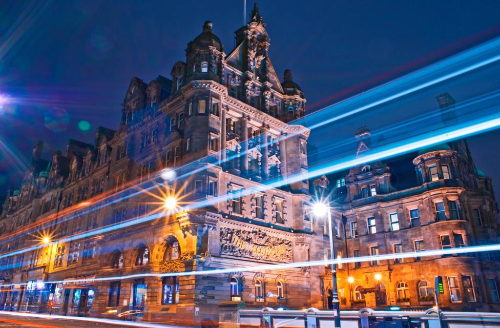 un gran edificio con luces delante de él por la noche en The Scotsman Hotel, en Edimburgo