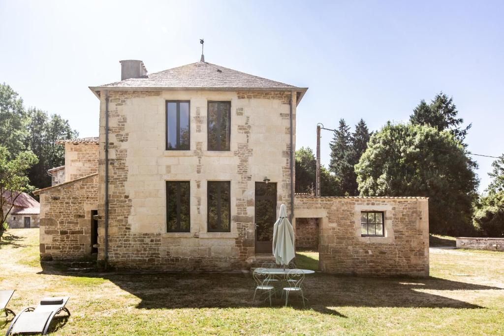 a brick house with a table and an umbrella at La Maison des mariés - Nature & Sèvre Niortaise in Sciecq