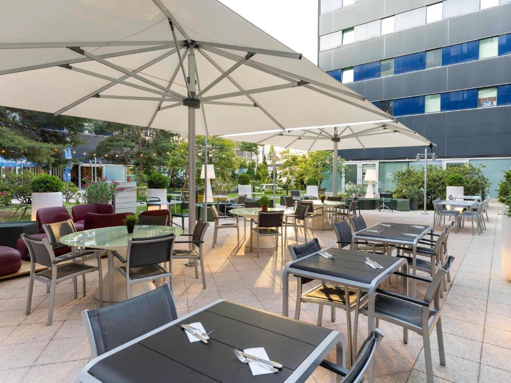 an outdoor patio with tables and chairs and umbrellas at Novotel Zurich City West in Zurich