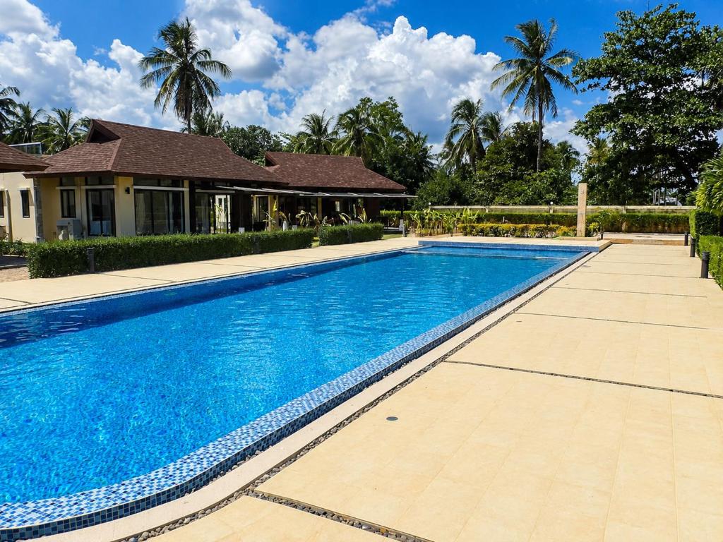 a large blue swimming pool in front of a house at Chaba Villa at Had Yao Beach in Had Yao Beach