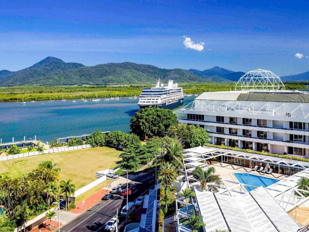 a cruise ship in a river next to a resort at Pullman Reef Hotel Casino in Cairns