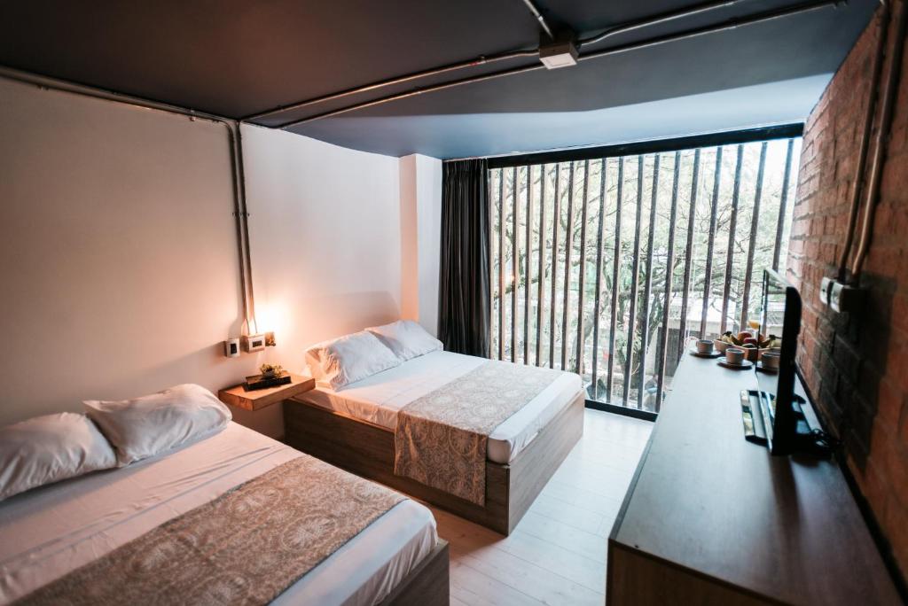 een slaapkamer met twee bedden en een groot raam bij Soy Local Provenza in Medellín