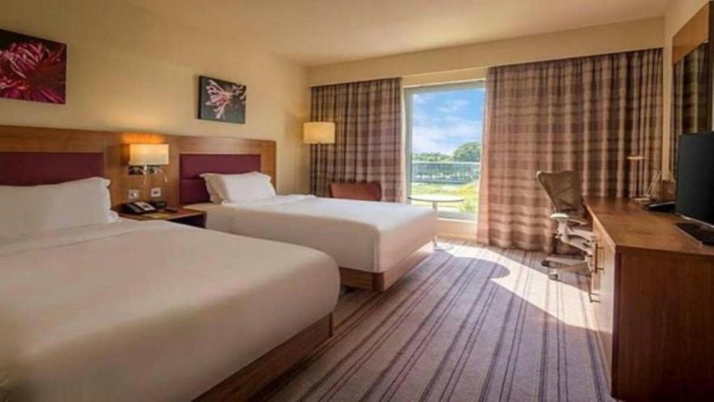 a hotel room with two beds and a television at Holiday Inn London Luton North in Luton