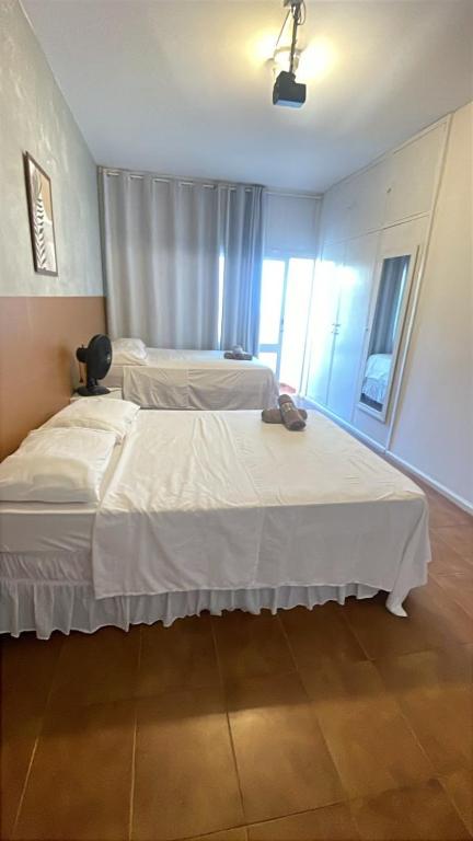 a bedroom with two beds with white sheets at Quarto com varanda privada a 160 metros da Praia do Farol da barra 3 in Salvador