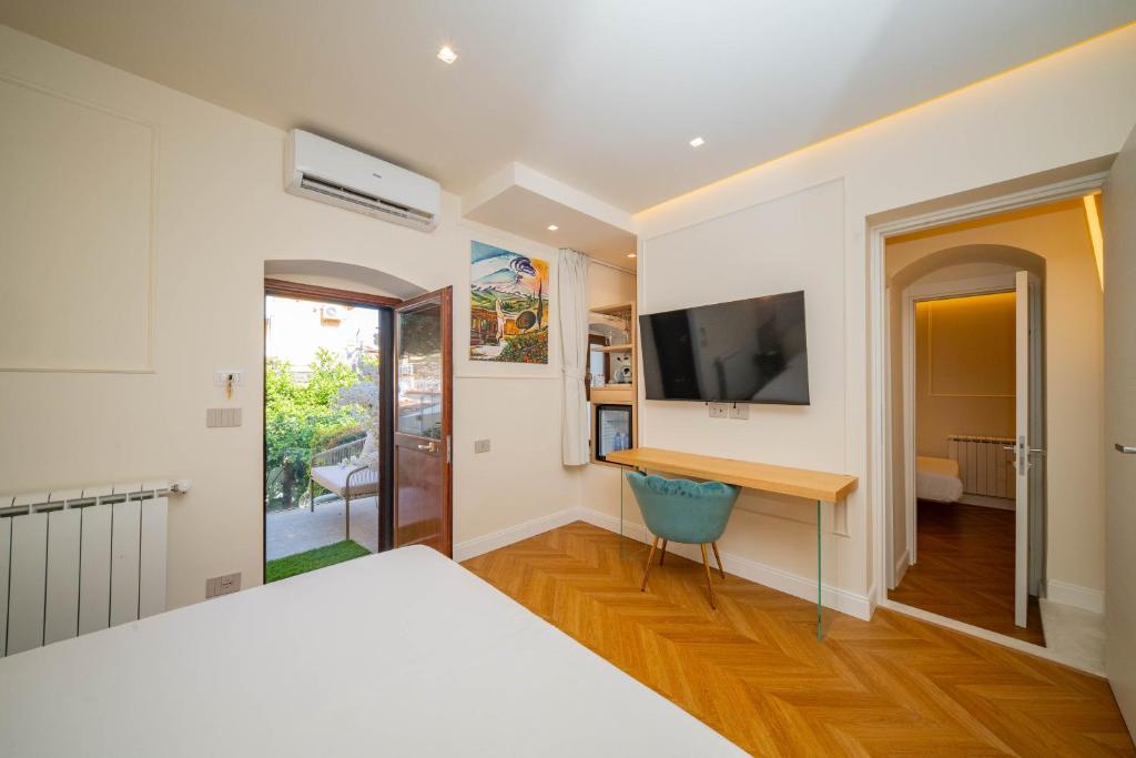 a bedroom with a bed and a desk and a television at Villa al Duomo Taormina - Suite & Rooms in Taormina