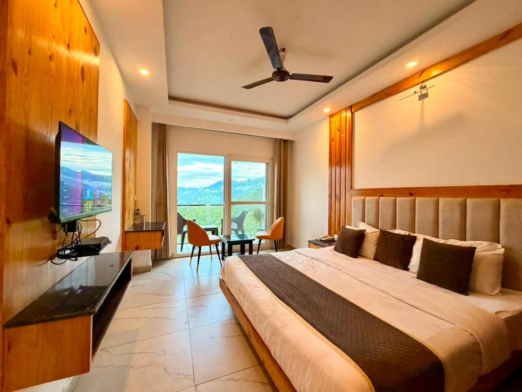 a bedroom with a large bed and a flat screen tv at Pine View Luxury Resort With Mountain View & Premium Rooms Mussoorie in Mussoorie