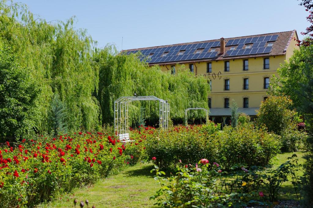 a garden with flowers and a building in the background at Hanul Moara cu Noroc in Ineu