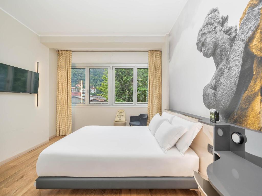 a bedroom with a white bed and a window at B&B Hotel Como City Center in Como