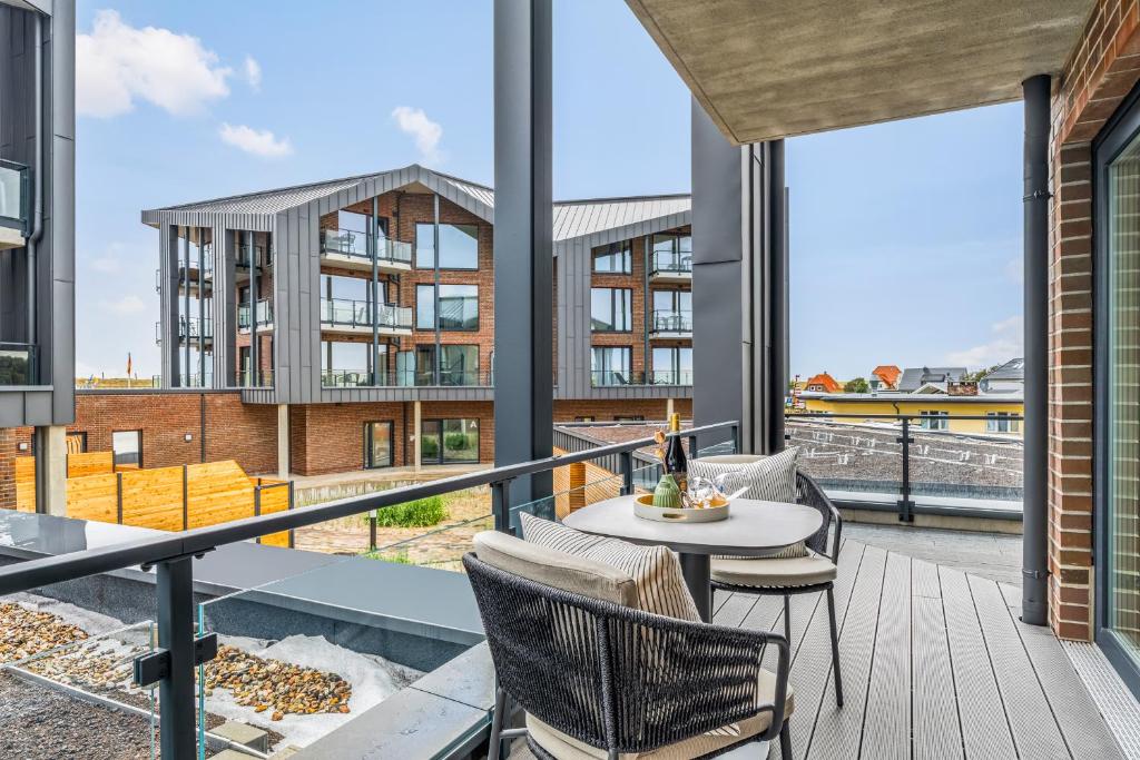 a balcony with a table and chairs and a building at Ferienwohnung TheViewC08 Hygge am Deich Dagebüll in Dagebüll
