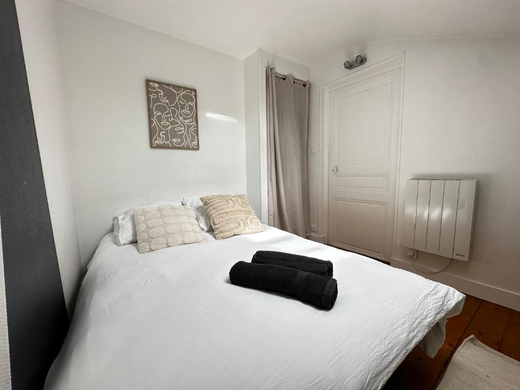 a white bed with two black towels on it at Studio Cosy & Chic in Angoulême
