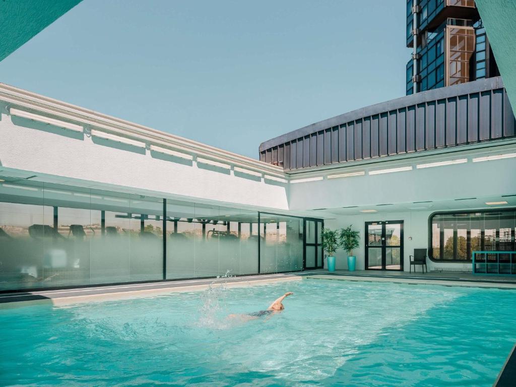 a person swimming in a swimming pool next to a building at Novotel Paris Centre Tour Eiffel in Paris