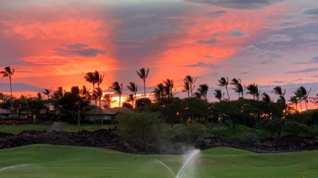 a sunset over a golf course with palm trees at Mauna Lani Fairways 903 in Waikoloa