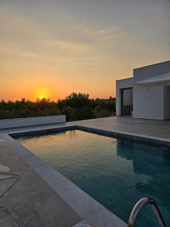a swimming pool with a sunset in the background at Elia Serenity House in Anarita