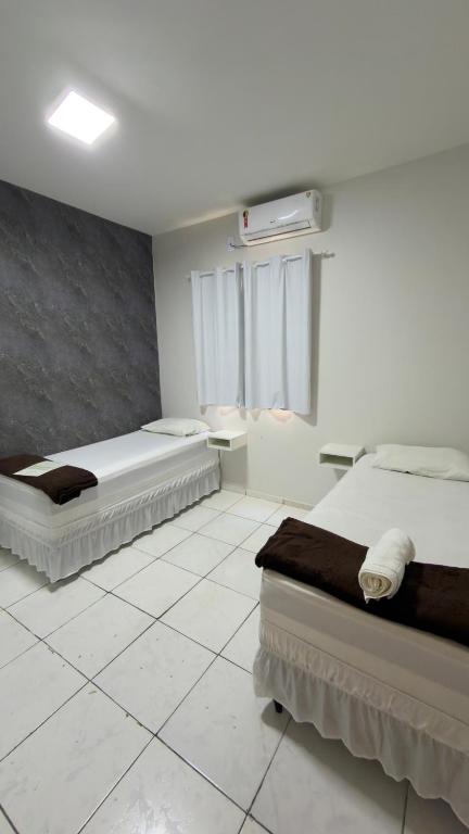 two beds in a room with white tile floors at Villas Hotel in Barreiras